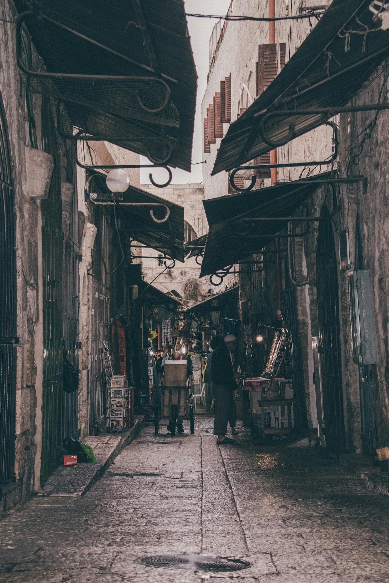 Explore the bustling atmosphere of a narrow market alleyway filled with shops and locals.